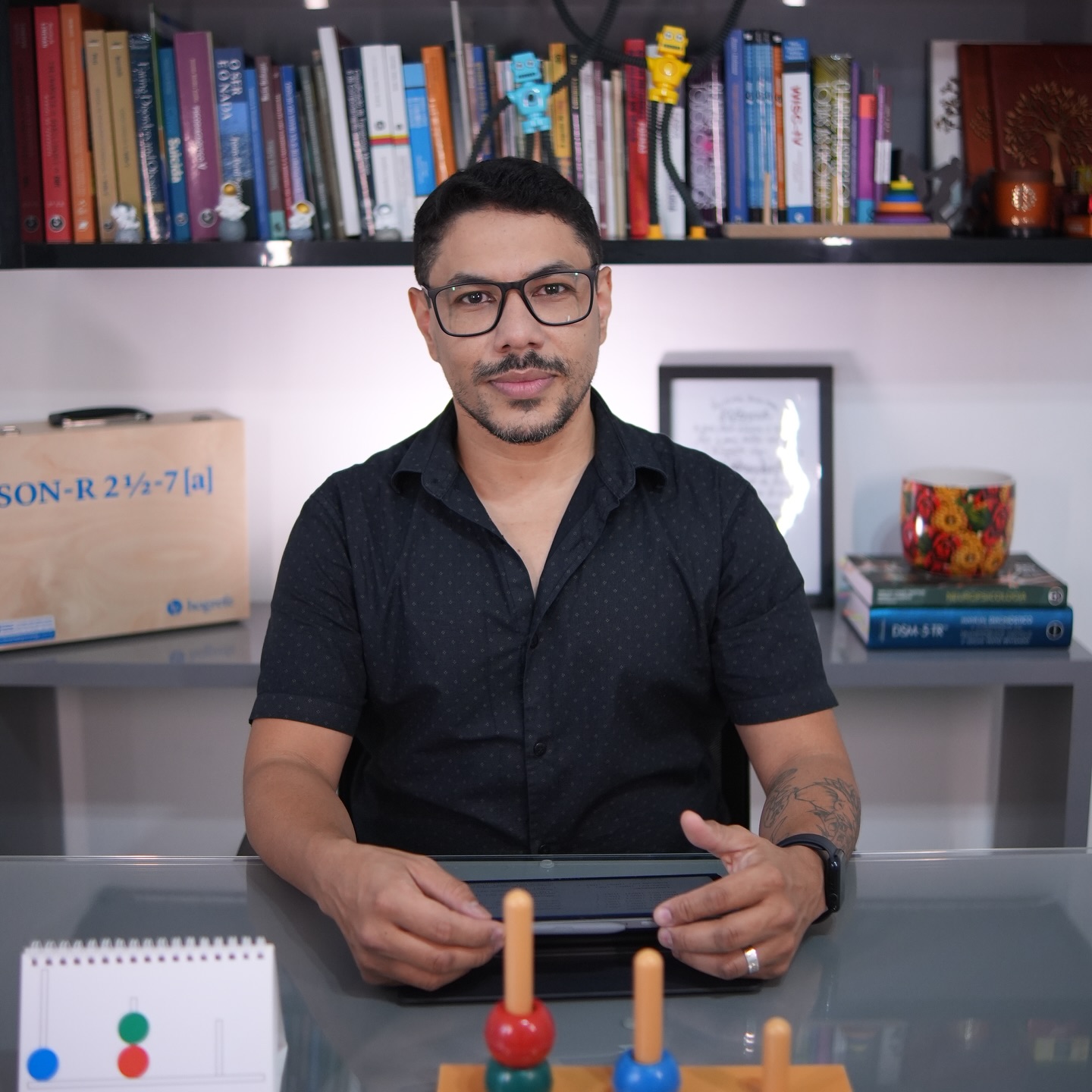 André Gonçalves em seu consultório, com instrumentos de avaliação neuropsicológica
